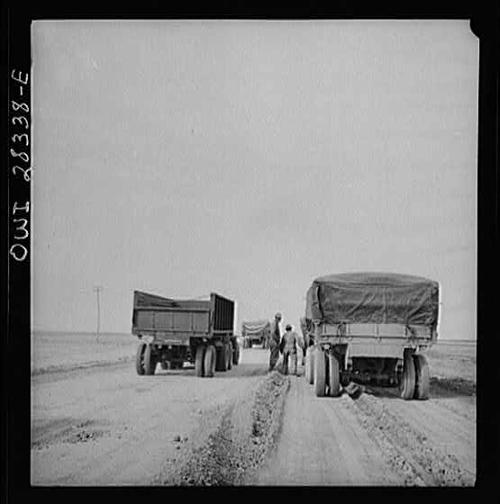 Somewhere in the Persian corridor. A United States Army truck convoy carrying supplies for Russia, moving by a disabled truck. This truck will be repaired by a crew of mechanics riding at the end of the convoy.
