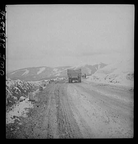 Somewhere in the Persian corridor. A United States Army truck convoy carrying supplies for the aid of Russia. A truck near the top of the snow-covered mountain making the difficult climb. An Iranian native is leading his livestock on the road.